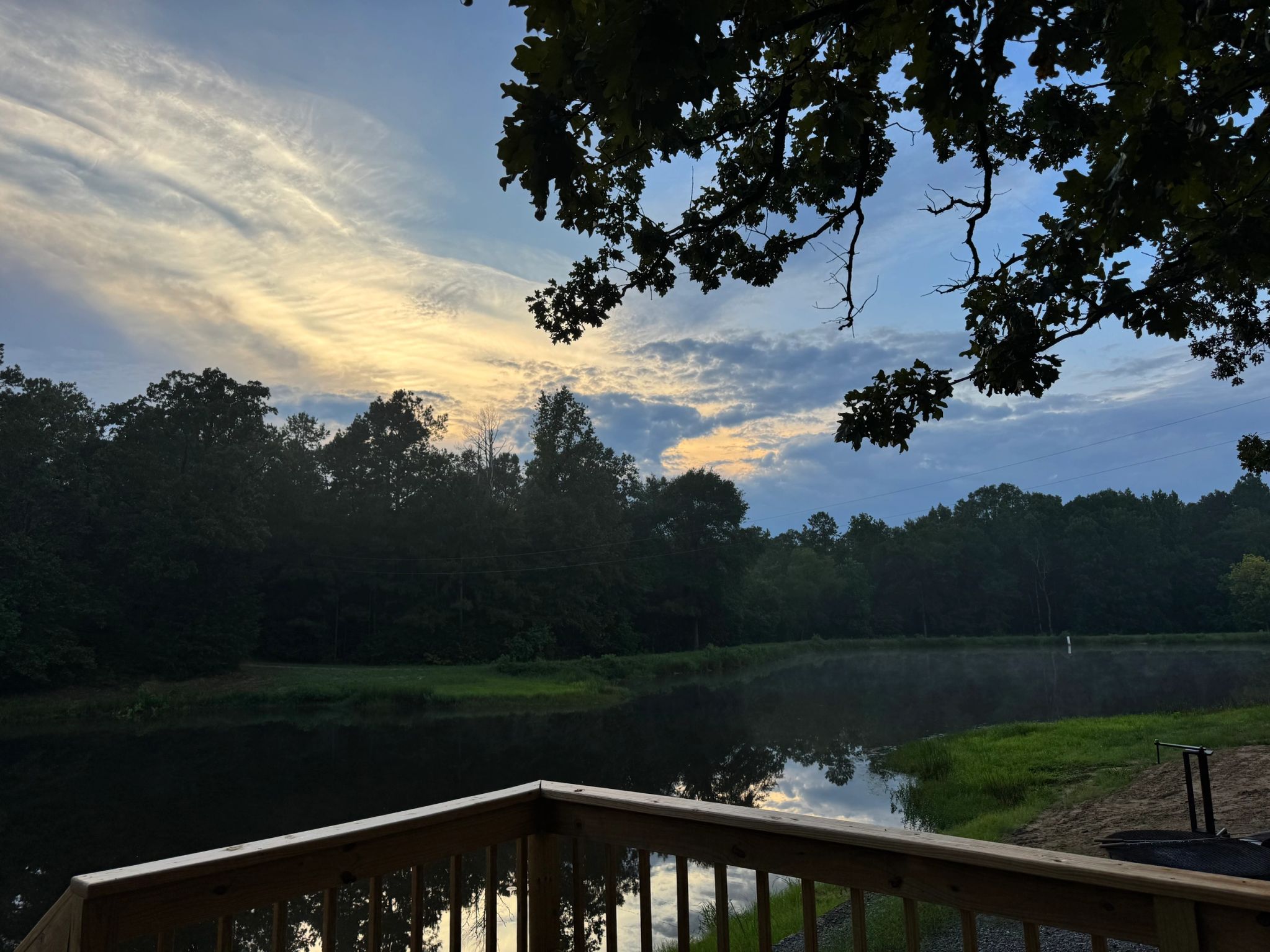 Deck and dock railing view over the water with fire pit on the bank